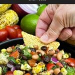 Tortilla chip scooping up Cowboy Caviar from a serving bowl.