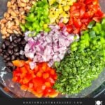 Fresh vegetables, beans, and corn tossed together in a large bowl before adding the dressing for Cowboy Caviar.