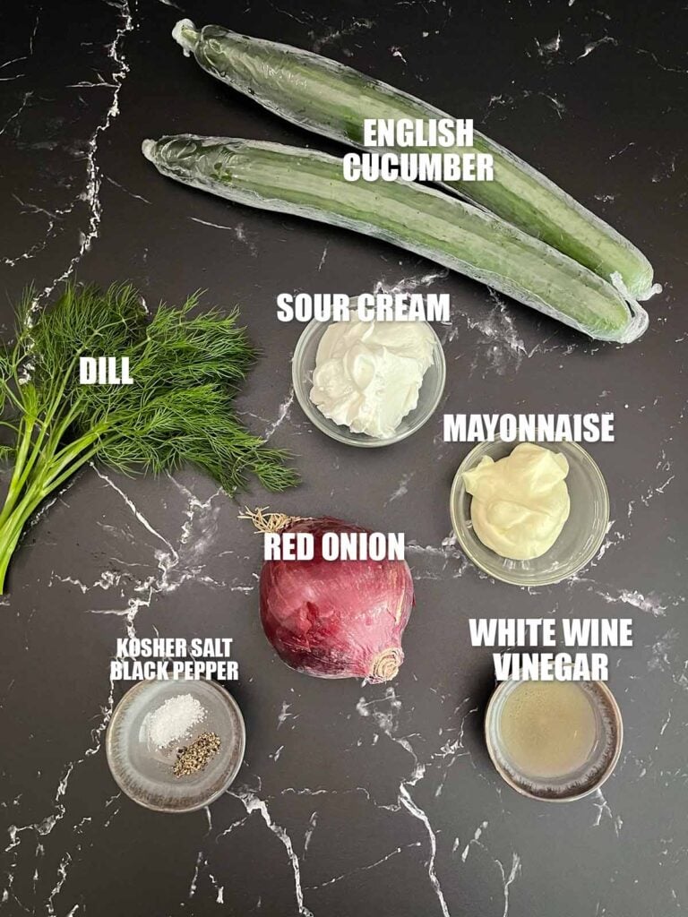 Ingredients for creamy cucumber salad including English cucumbers, red onion, sour cream, mayonnaise, fresh dill, white wine vinegar, salt, and pepper.