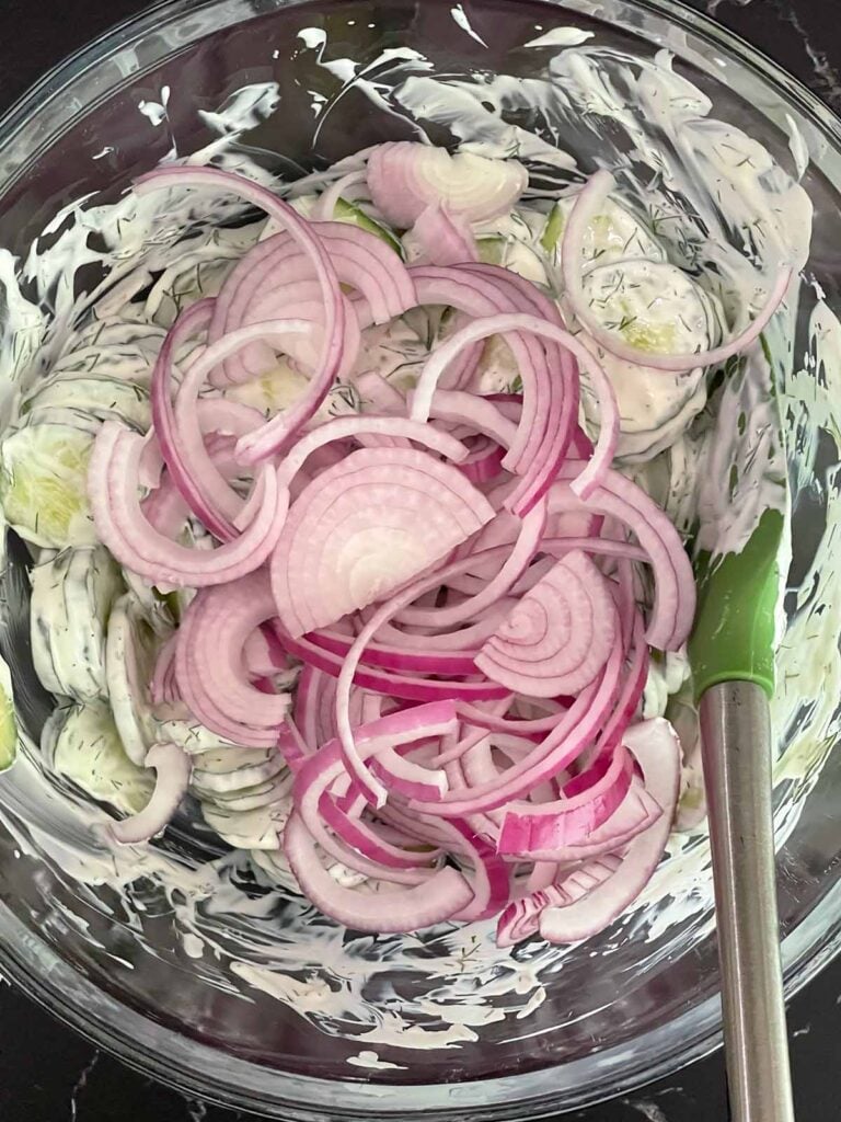 Sliced cucumbers and red onion added to creamy dill dressing.