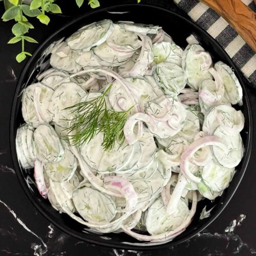 Creamy cucumber salad with fresh dill and red onion ready to serve.