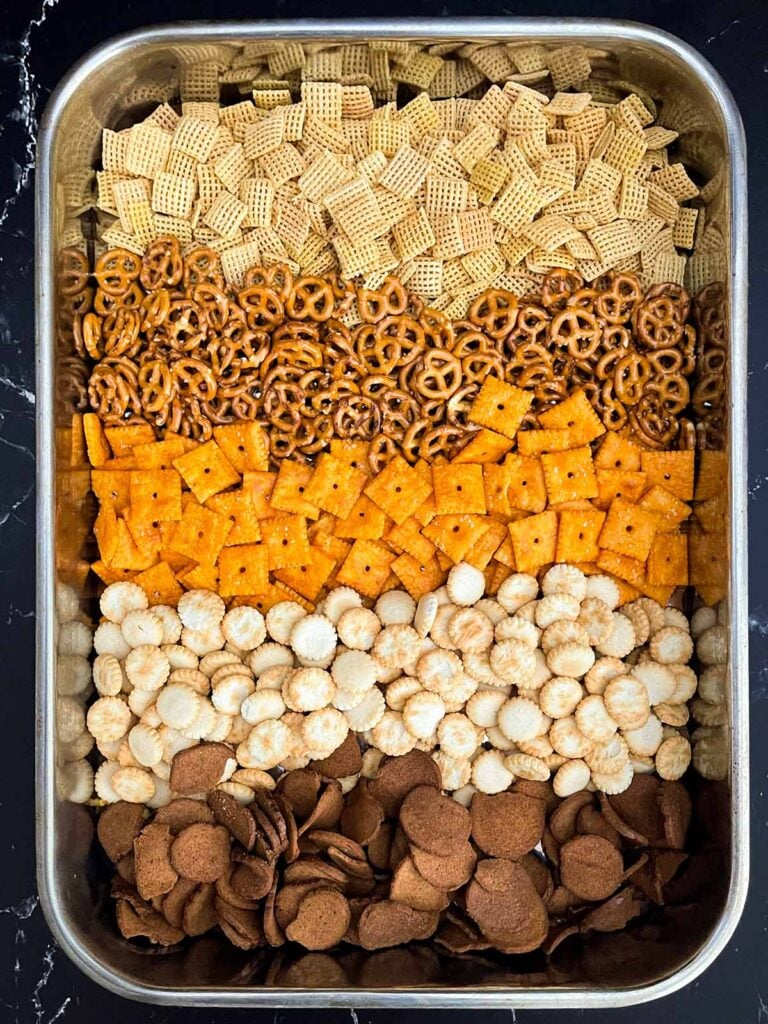 Corn Chex cereal, oyster crackers, pretzels, cheddar crackers, and garlic rye chips in a large roasting pan.