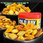 Easy Old Bay Snack Mix served in a black bowl with Corn Chex cereal, pretzels, oyster crackers, cheddar crackers, and garlic rye chips.