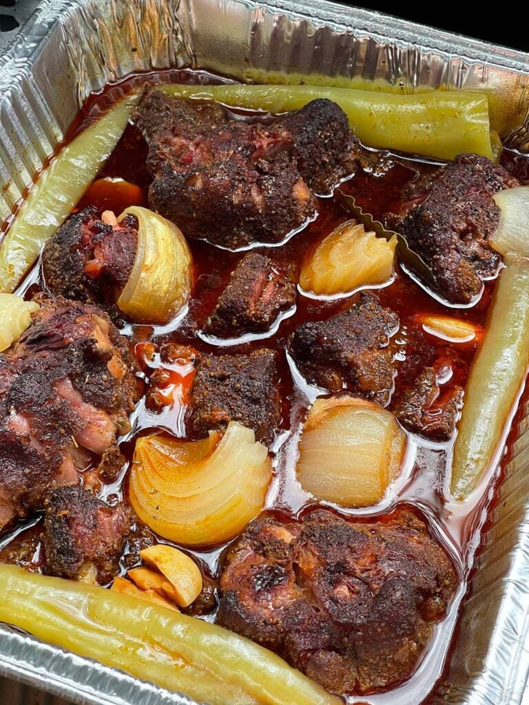 Braised smoked oxtail in an aluminum tray.