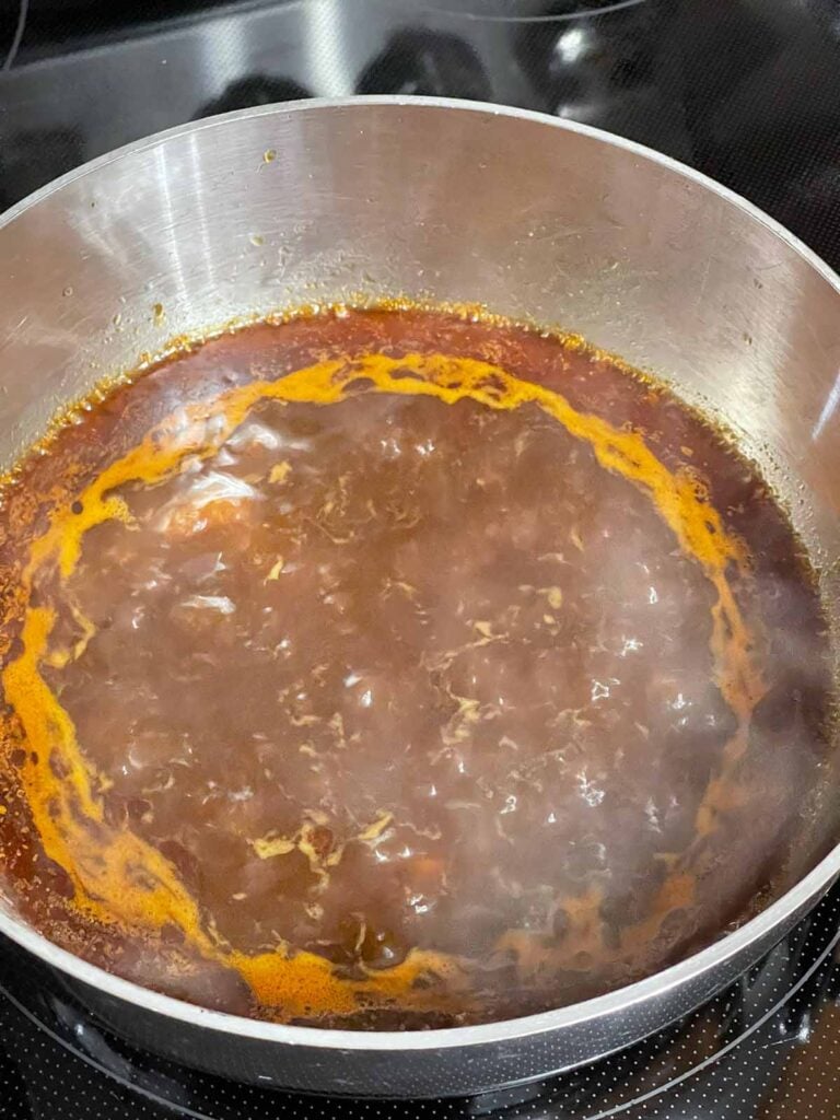 Oxtail braising liquid simmering on the stove.