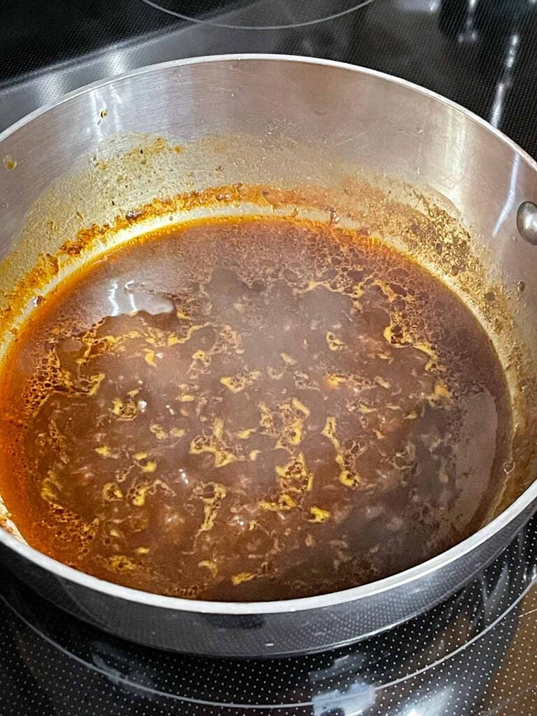 Oxtail braising liquid being reduced on the stove.
