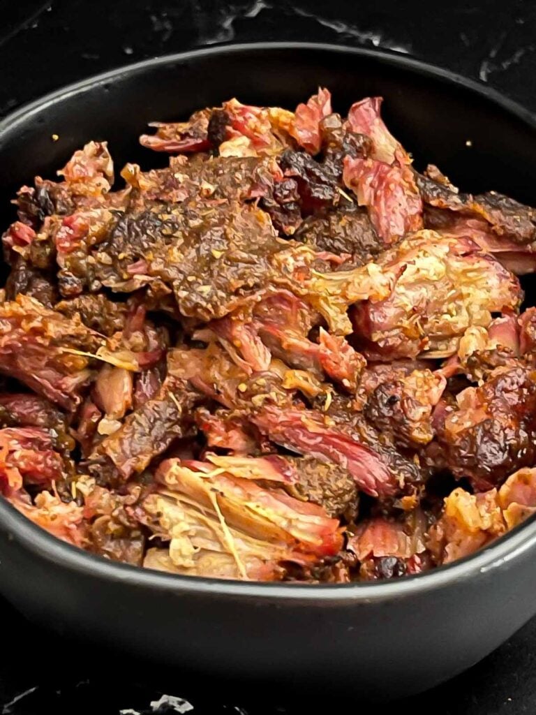 Smoked oxtail meat in a dark bowl.
