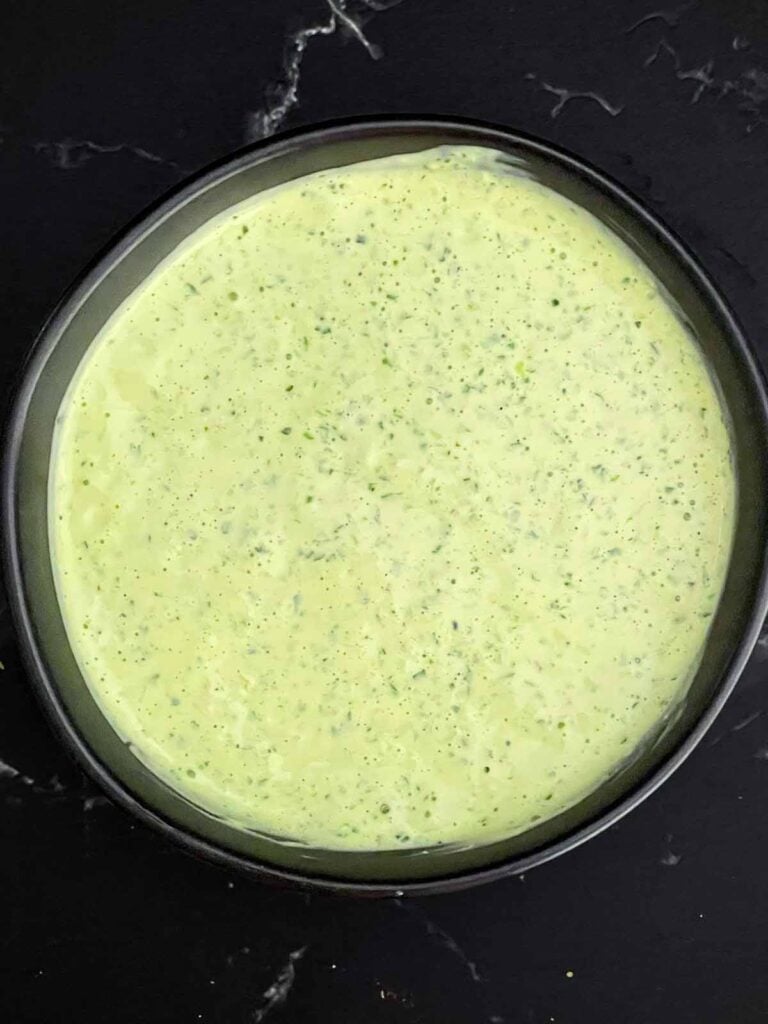 Jalapeno cilantro sauce in a dark bowl.