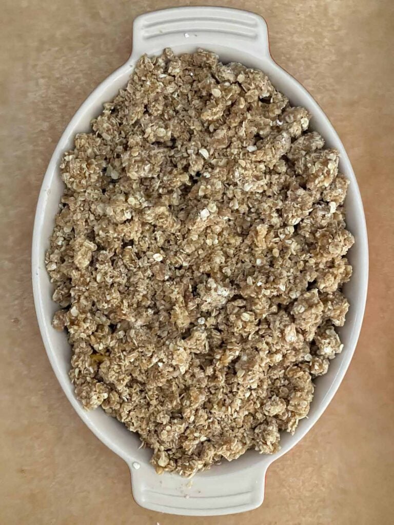 Peach and blueberry filling spread into a buttered baking dish and topped evenly with the buttery oat crumble.