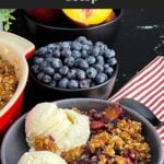 Golden brown Easy Peach Blueberry Crisp with a buttery oat topping served warm in a grey bowl with a scoop of vanilla ice cream melting over the fruit.