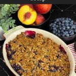 Freshly baked Easy Peach Blueberry Crisp in a red baking dish with a golden brown oat topping and bubbling peach and blueberry filling before serving.