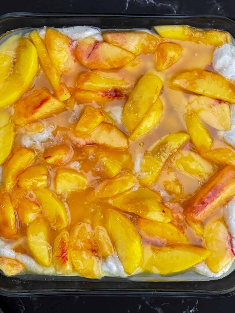 Sweetened peach slices arranged evenly over the cobbler batter before baking.