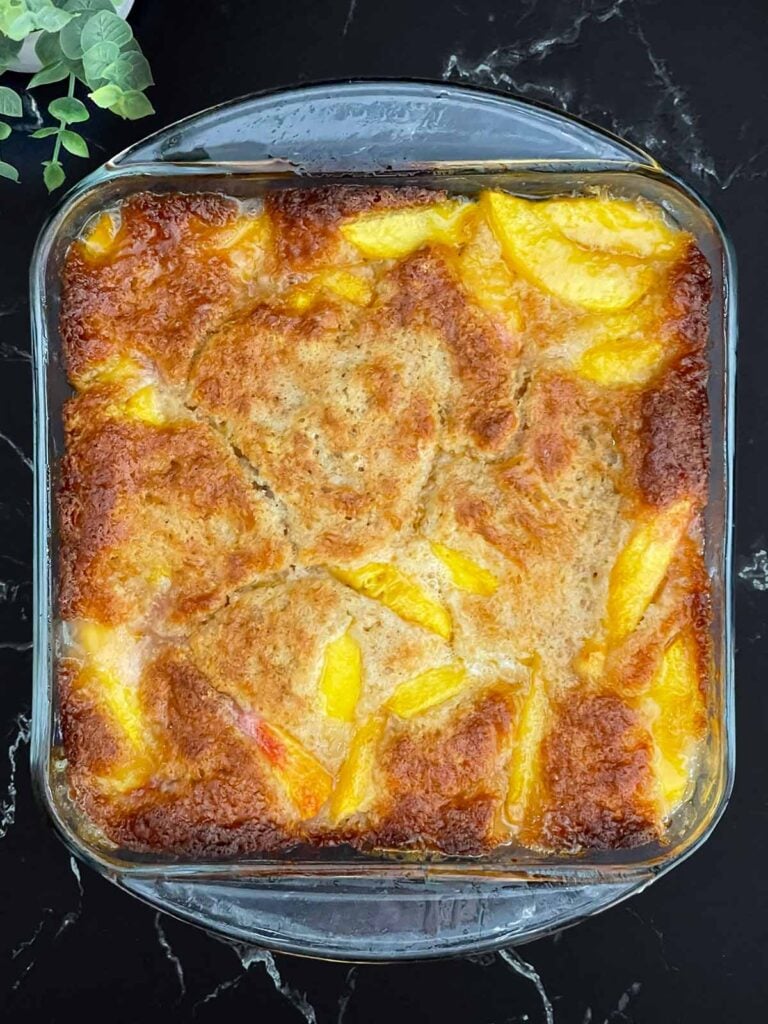 Homemade peach cobbler with a golden buttery crust and juicy peaches fresh from the oven.