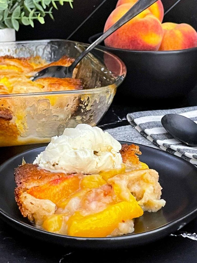 Warm serving of old-fashioned peach cobbler topped with a scoop of vanilla ice cream.
