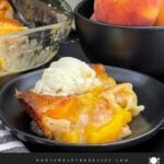 A scoop of old-fashioned peach cobbler topped with a scoop of vanilla ice cream.