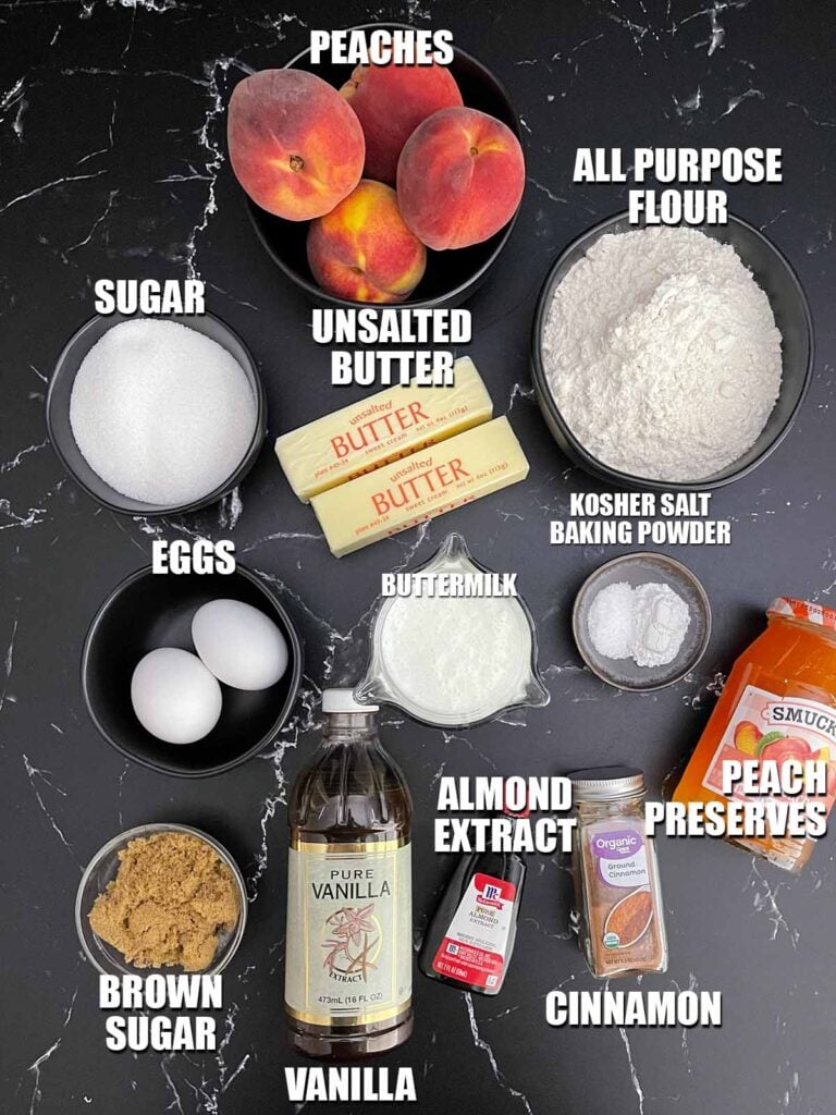 Ingredients for homemade peach muffins including fresh peaches, flour, sugar, dark brown sugar, kosher salt, baking powder, vanilla , almond extract, butter, buttermilk, eggs, peach preserves, and cinnamon.