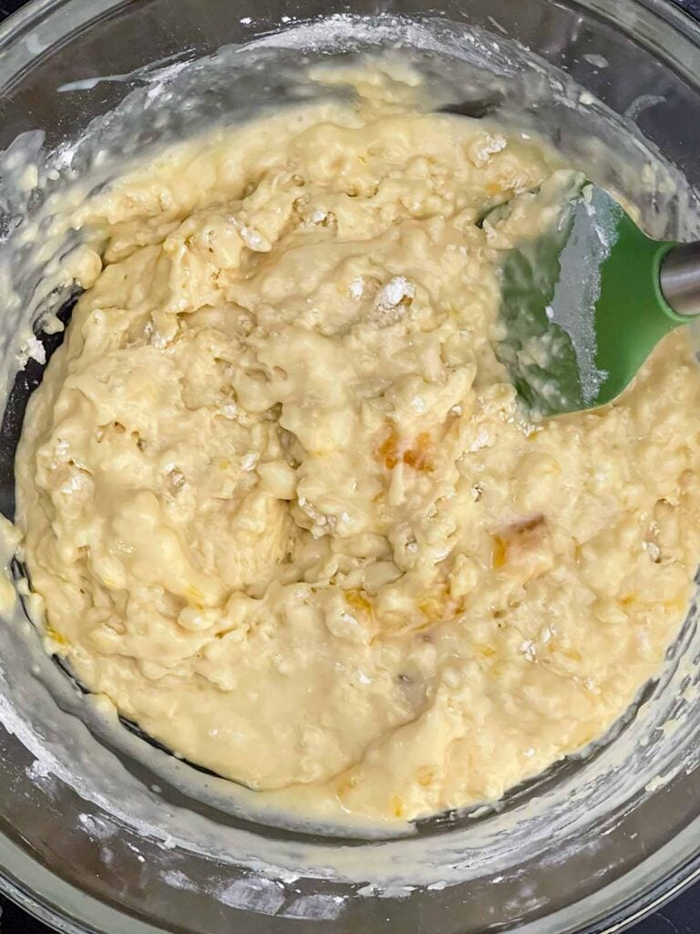 Homemade peach muffin batter mixed in a glass bowl.