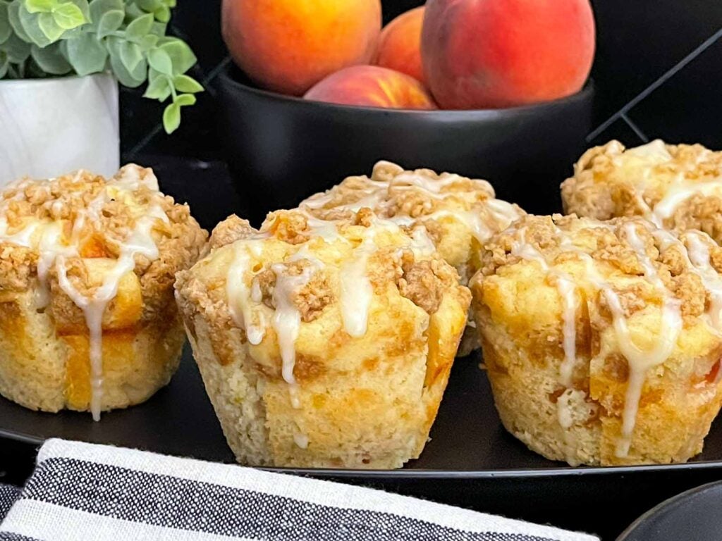 Soft and fluffy peach muffins made with fresh peaches, peach preserves, cinnamon streusel, and peach glaze.