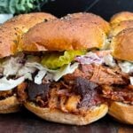 Close-up of homemade pulled pork sliders with barbecue sauce, creamy coleslaw, and dill pickles.