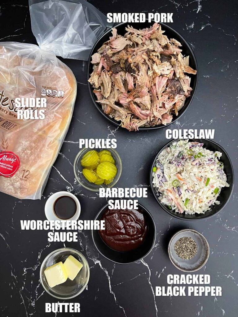 Ingredients for pulled pork sliders including savory slider rolls, pulled pork, barbecue sauce, coleslaw, dill pickles, Worcestershire sauce, and cracked black pepper.