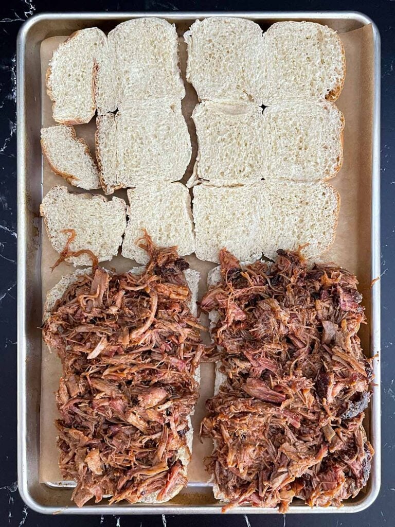 Barbecue pulled pork spread evenly over the bottom half of slider rolls.