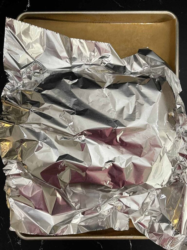 Pulled pork sliders covered with aluminum foil before baking.