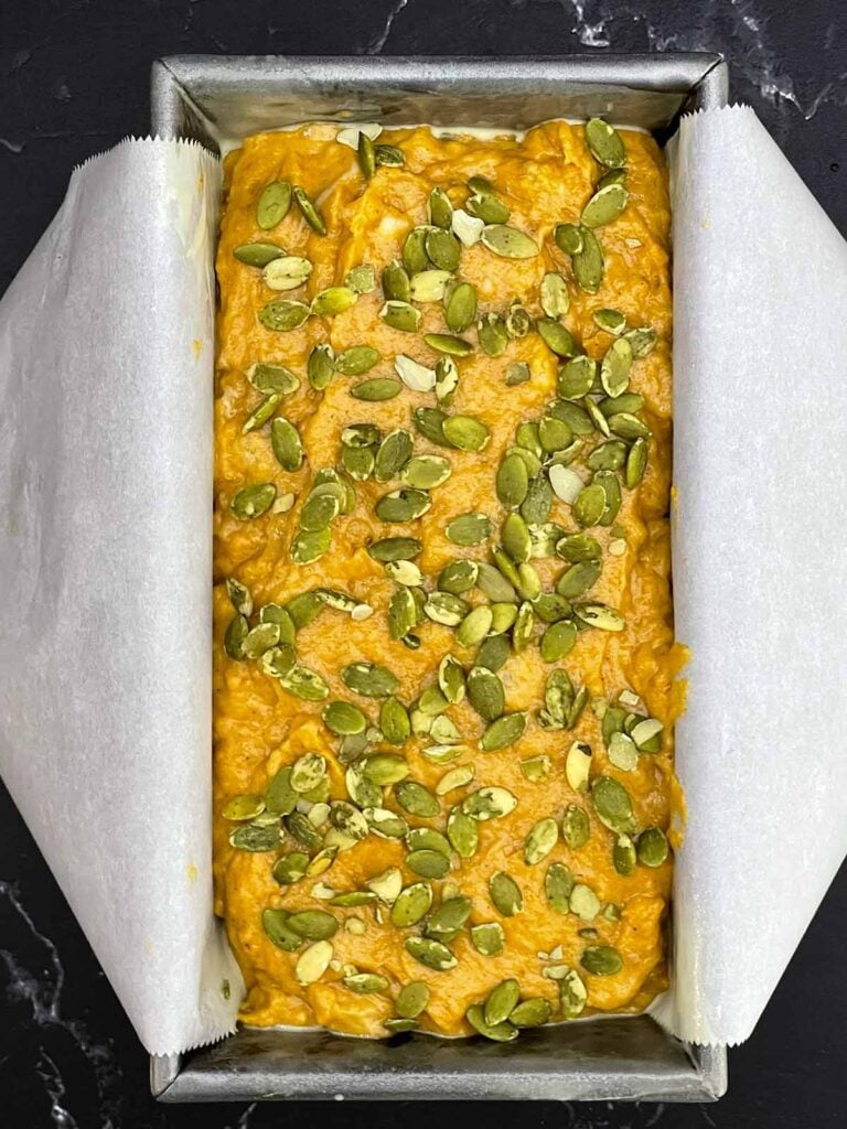 Pumpkin banana bread batter topped with pumpkin seeds before baking.