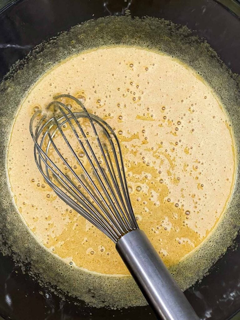 Eggs and sugars whisked in a bowl for cinnamon apple muffin batter.