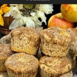 Apple cinnamon muffins with cinnamon sugar tops stacked in a cake pan lined with parchment paper.