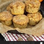 Homemade apple cinnamon muffins with cinnamon sugar tops stacked in a cake pan lined with parchment paper.