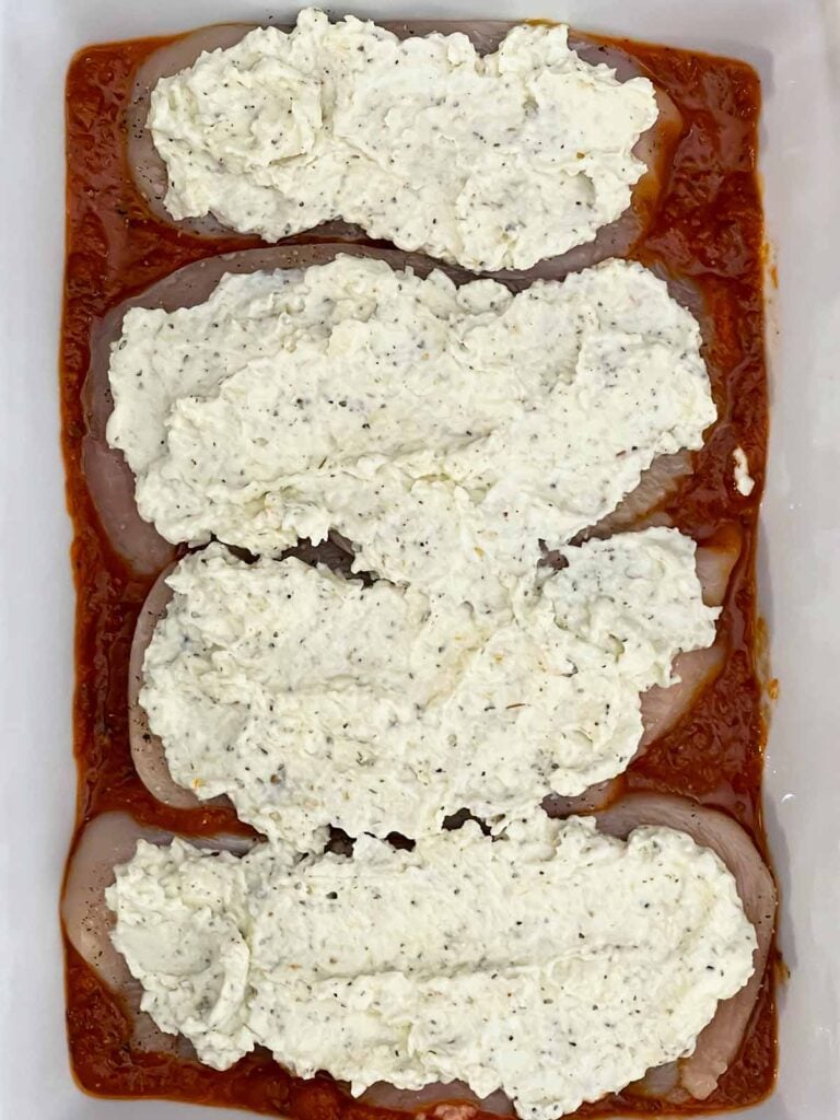 Chicken breasts topped with seasoned ricotta cheese mixture before baking.