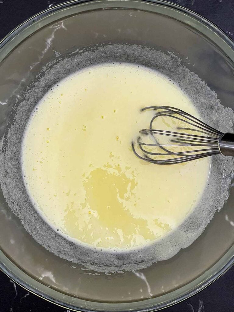 Eggs and granulated sugar whisked together in a large mixing bowl.