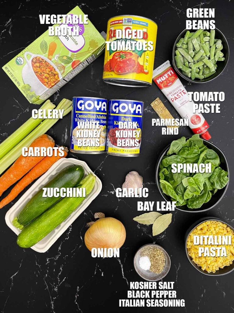 Ingredients for slow cooker minestrone soup including vegetables, beans, tomatoes, ditalini pasta, and vegetable stock.
