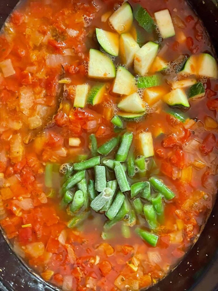 Diced zucchini and green beans added to minestrone soup in the slow cooker.