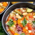 Bowl of slow cooker minestrone soup with ditalini pasta, vegetables, beans, and spinach.