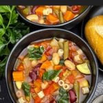 Slow cooker minestrone soup with vegetables, beans, spinach, and ditalini pasta in tomato broth.