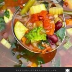 Finished minestrone soup with tender vegetables, beans, spinach, and tomato broth in the slow cooker.