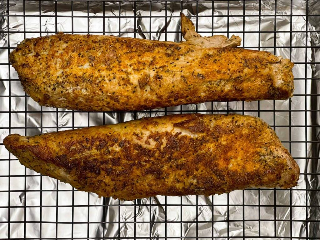 Seared pork tenderloins on a wire rack over a foil-lined baking sheet before roasting.