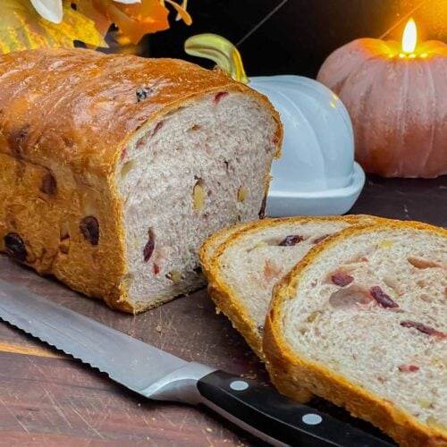Sliced cranberry walnut bread on a cutting board showing the cranberries and walnuts throughout the loaf.