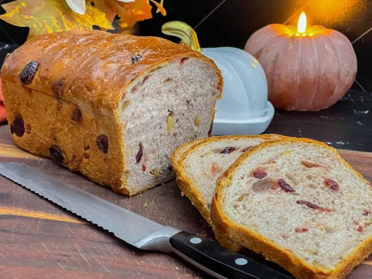 Sliced cranberry walnut bread on a cutting board showing the cranberries and walnuts throughout the loaf.