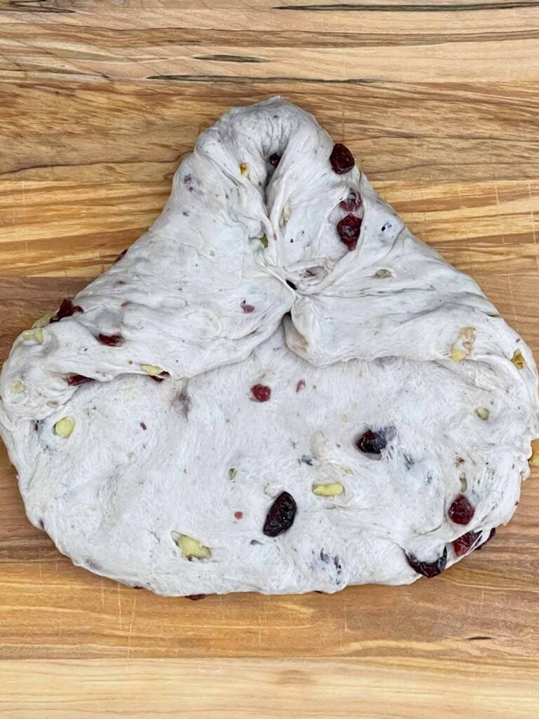 Cranberry walnut bread dough being folded and shaped into a loaf.
