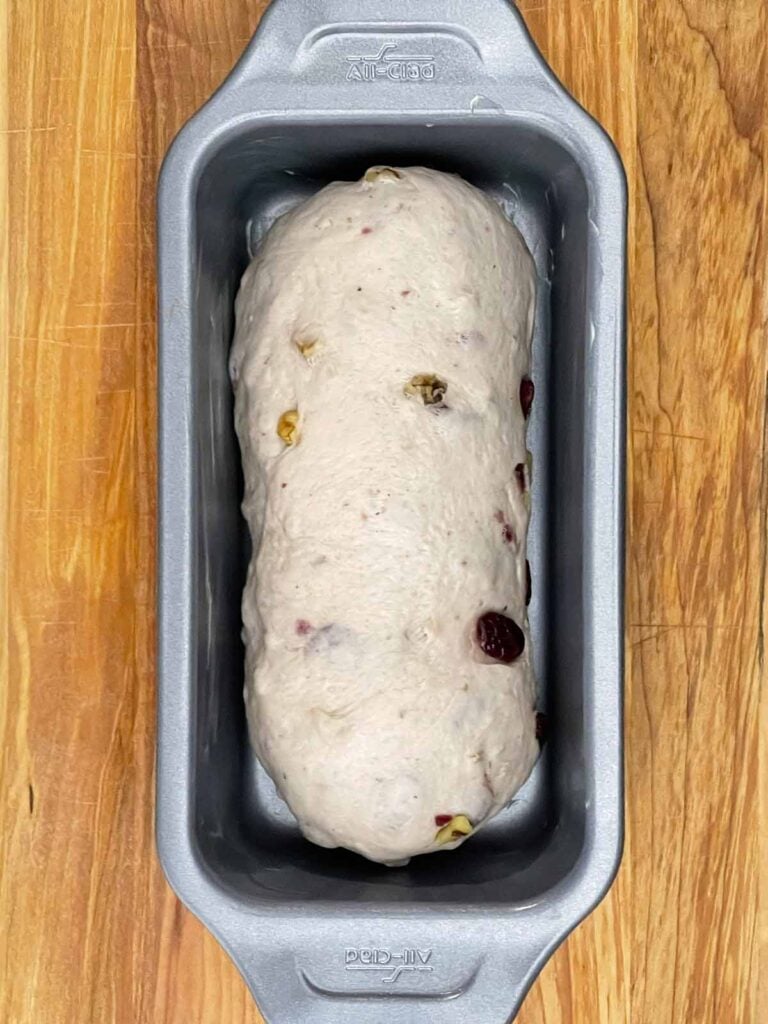 Shaped cranberry walnut bread dough placed in a loaf pan.