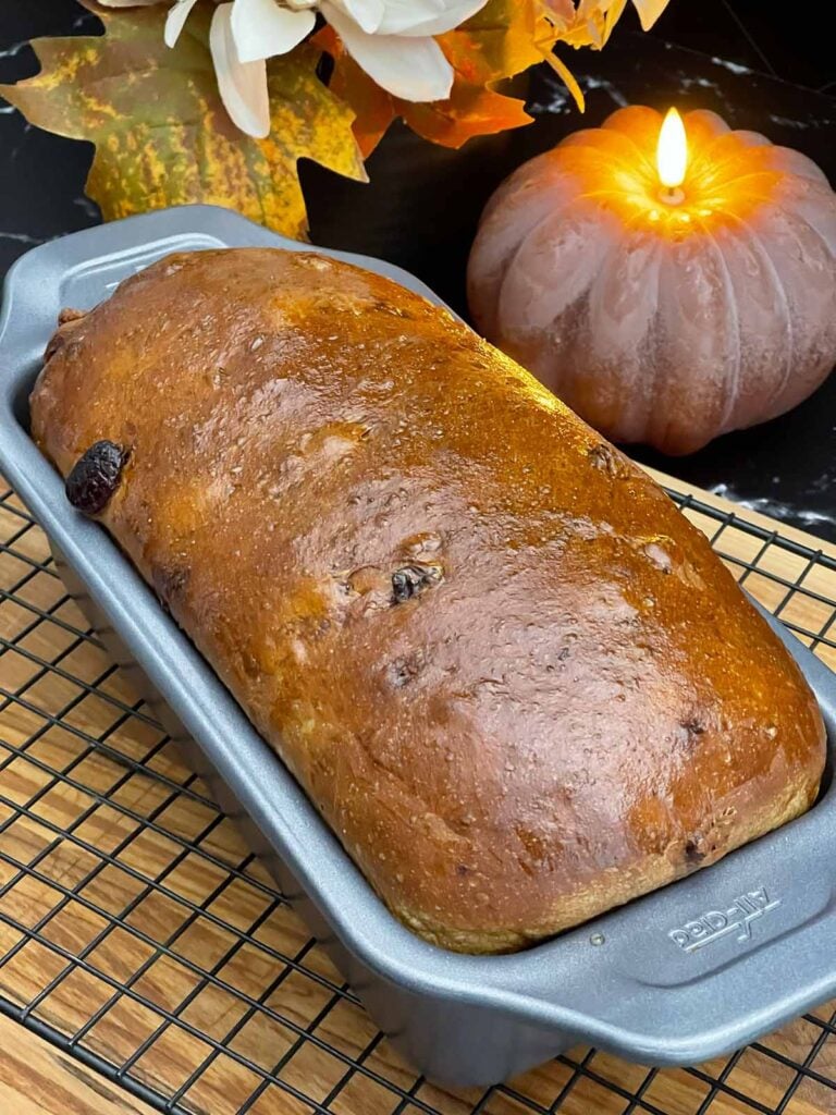 Freshly baked cranberry walnut bread in the loaf pan with a golden brown crust.