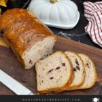 Sliced cranberry walnut bread on a cutting board showing the cranberries and walnuts throughout the loaf.