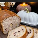 Sliced cranberry walnut bread on a cutting board showing the cranberries and walnuts throughout the loaf.