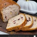 Sliced cranberry walnut bread on a cutting board showing the cranberries and walnuts throughout the loaf.