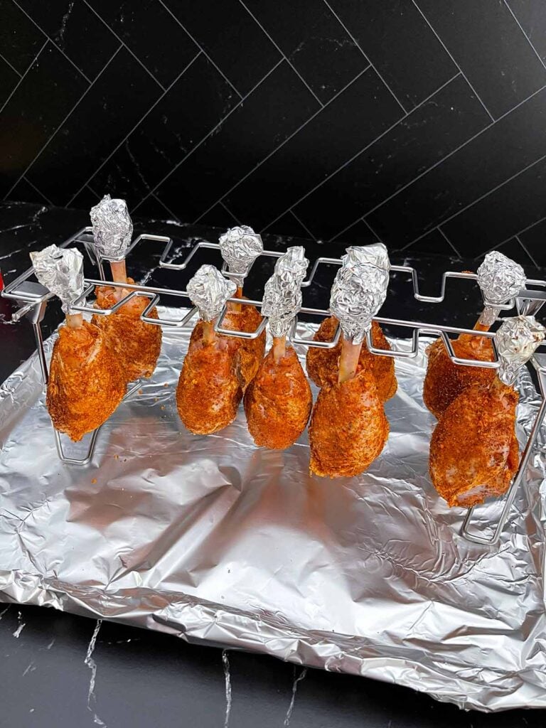 Chicken lollipops hanging from a rack and ready to go on the smoker.