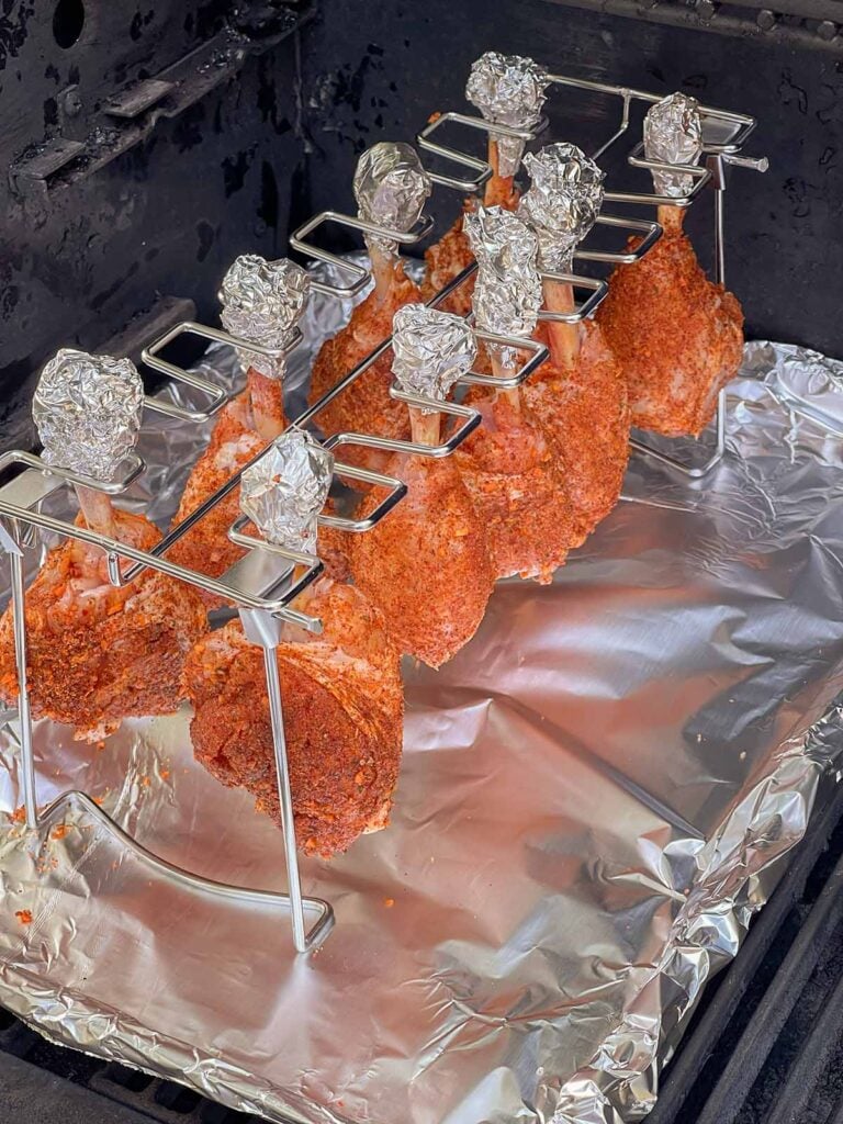 Chicken lollipops hanging from a rack and ready to go on the smoker.
