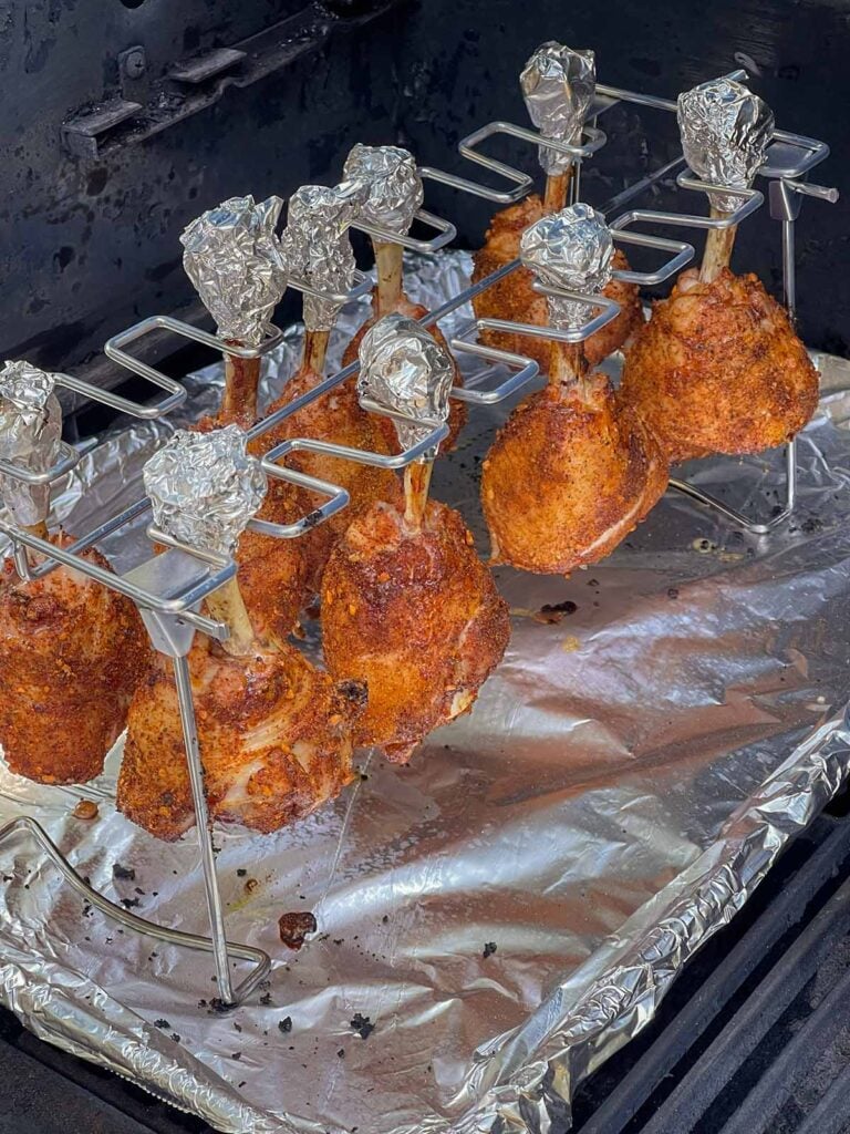 Chicken lollipops cooking on a hanging rack inside the smoker.
