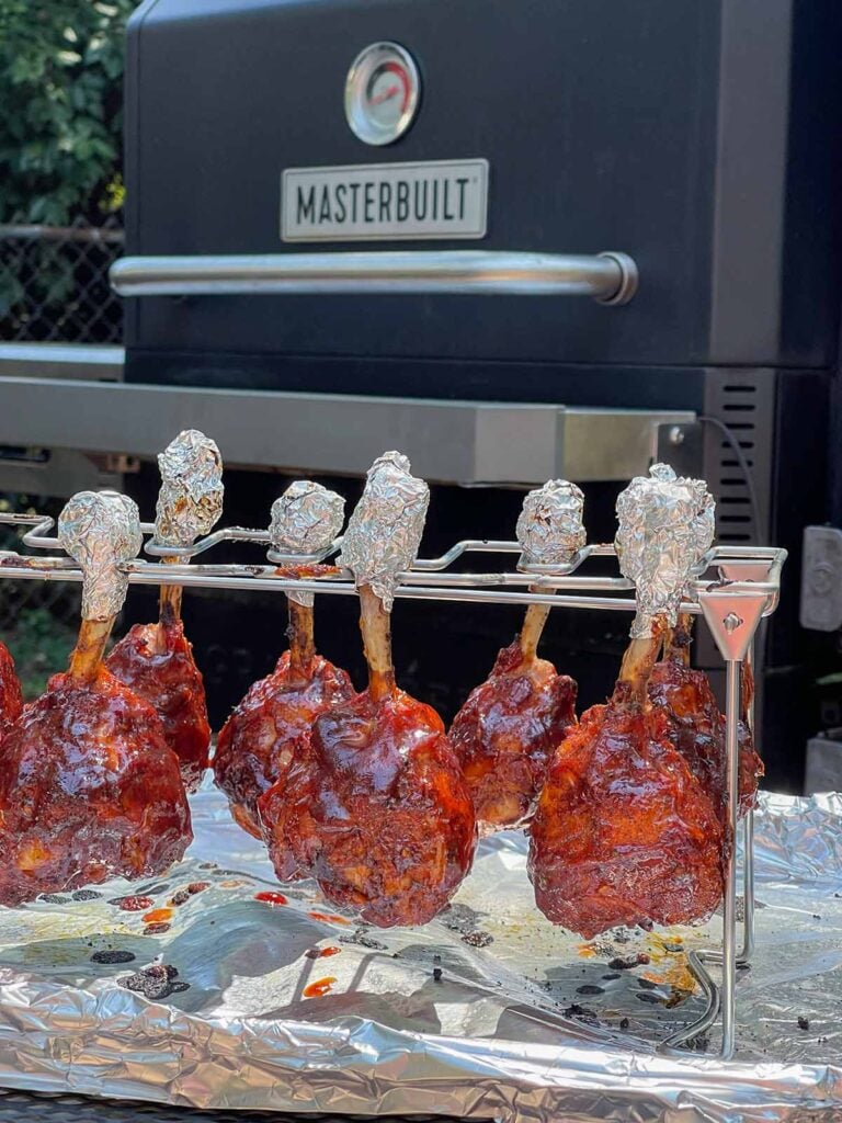 Finished smoked chicken lollipops hanging on the rack after being removed from the smoker.